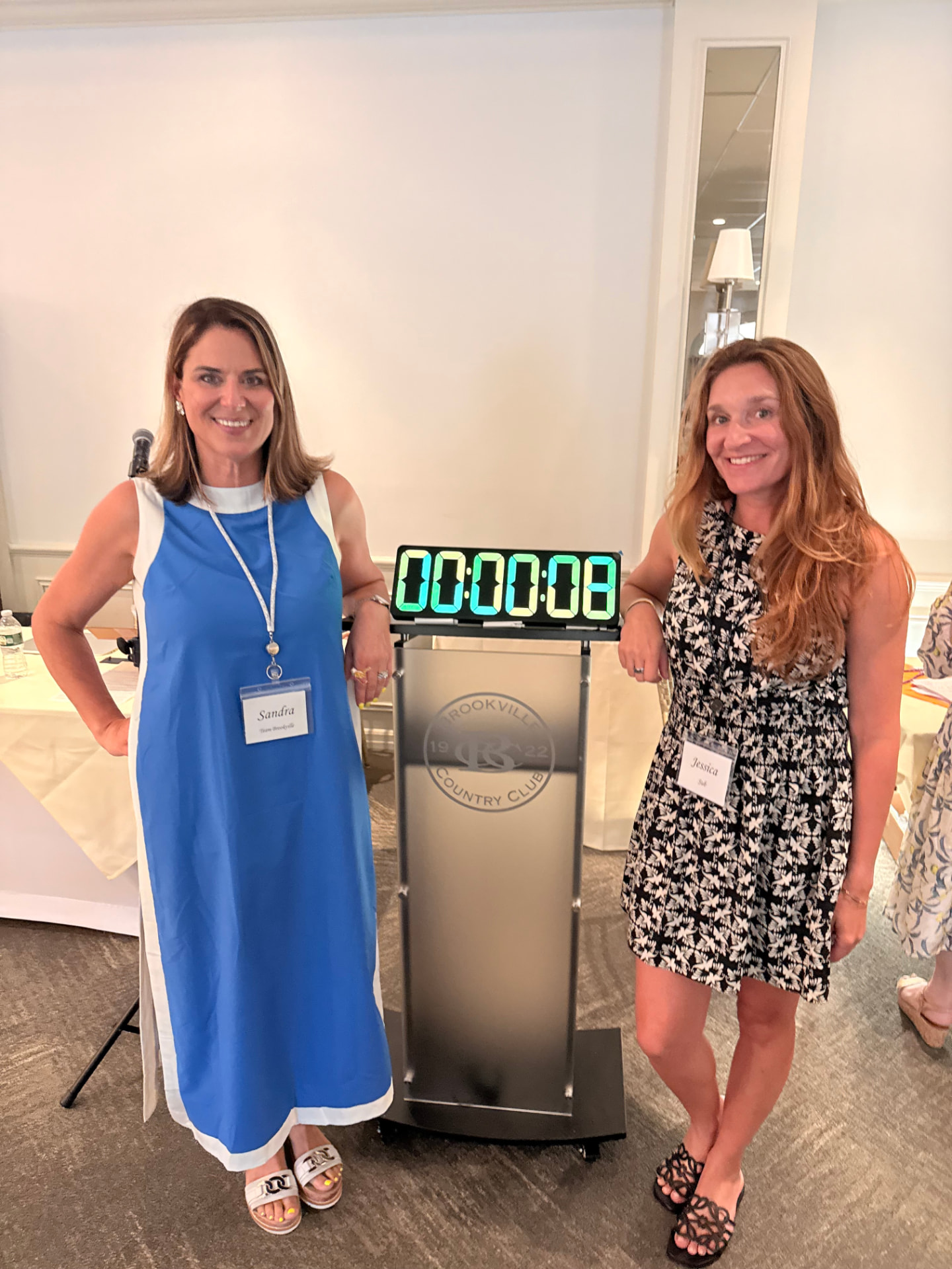 Sandra and Jessica beside a countdown clock on a podium at Brookville Country Club