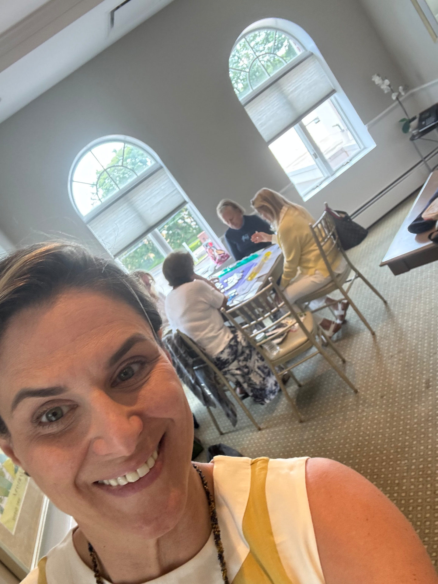 Sandra smiling during a lesson day at the country club, tables of players behind her
